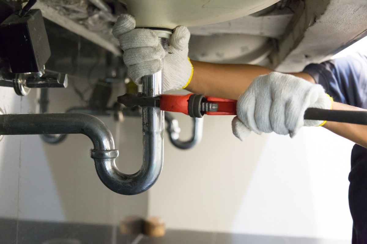 Plumber fitting a sink waste pipe with an adjustable wrench